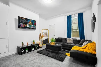 a living room with a couch and a tv at Anfield Four-Bed Spacious Getaway Haus in Liverpool