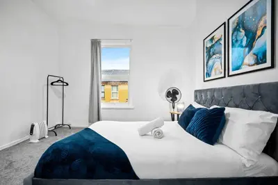 a bedroom with a large bed with blue pillows at Anfield Four-Bed Spacious Getaway Haus in Liverpool