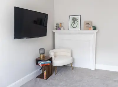 a living room with a white chair and a tv at No 45 Roscoe St in Liverpool