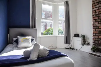 a bedroom with a bed with blue walls and windows at Large 4-Bedroom House, 6 Beds, Comfortable Home-from-Home, Great Deals in Wallasey