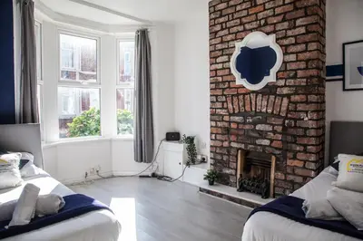 a living room with two beds and a brick fireplace at Large 4-Bedroom House, 6 Beds, Comfortable Home-from-Home, Great Deals in Wallasey