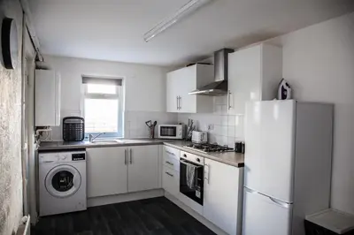 a white kitchen with a refrigerator and a dishwasher at Large 4-Bedroom House, 6 Beds, Comfortable Home-from-Home, Great Deals in Wallasey
