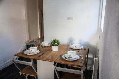 a wooden table with plates and cups on it at Large 4-Bedroom House, 6 Beds, Comfortable Home-from-Home, Great Deals in Wallasey