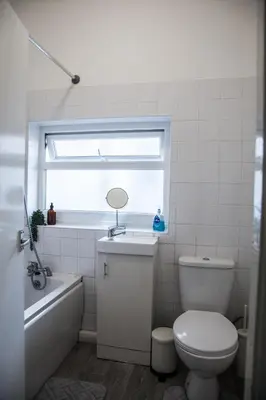 a bathroom with a toilet and a sink and a window at Large 4-Bedroom House, 6 Beds, Comfortable Home-from-Home, Great Deals in Wallasey