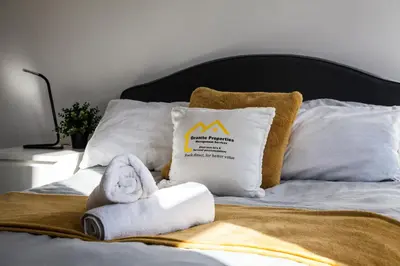 a bed with towels and a pillow with a mountain sign at Large 4-Bedroom House, 6 Beds, Comfortable Home-from-Home, Great Deals in Wallasey