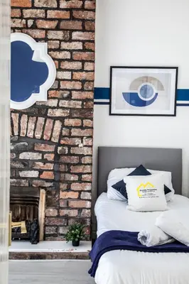 a bedroom with a brick wall and a bed at Large 4-Bedroom House, 6 Beds, Comfortable Home-from-Home, Great Deals in Wallasey