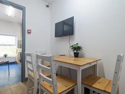 a table and chairs with a television on a wall at Room Near City Centre Private Bath Free Parking in Liverpool
