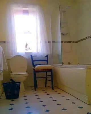 a bathroom with a toilet and a tub and a window at Marjorie's Cottage in Ulverston