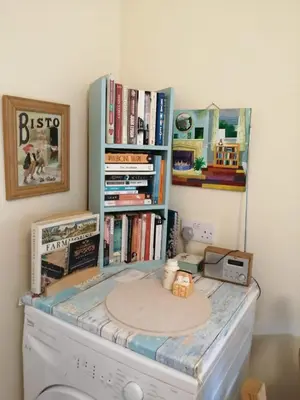 a laundry room with a book shelf with books at Marjorie's Cottage in Ulverston