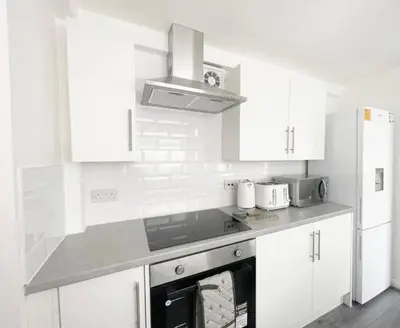 a kitchen with white cabinets and a stove top oven at Residency serviced accomodation liverpool in Litherland