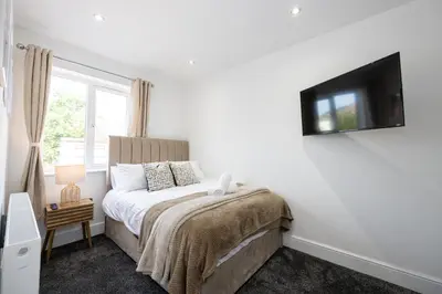 a bedroom with a bed and a tv on the wall at Cozy Modern Home Games Room & Cinema Perfect for 8 in Bolton