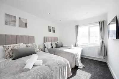 a bedroom with two beds and a window at Cozy Modern Home Games Room & Cinema Perfect for 8 in Bolton