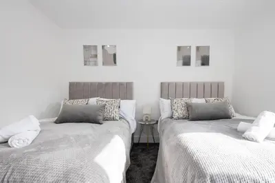 two beds sitting next to each other in a bedroom at Cozy Modern Home Games Room & Cinema Perfect for 8 in Bolton