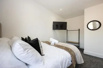 a white bed with black pillows and a mirror at Cozy Modern Home Games Room & Cinema Perfect for 8 in Bolton