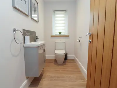 a bathroom with a toilet and a sink and a window at Treetops in Newton