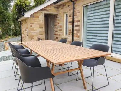 a wooden table and chairs on a patio at Treetops in Newton