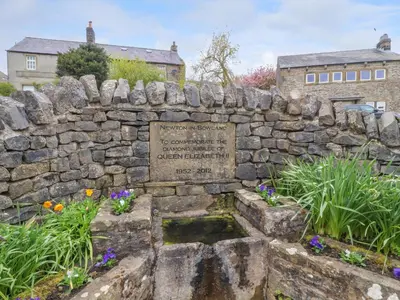 a stone wall with a sign in a garden at Treetops in Newton