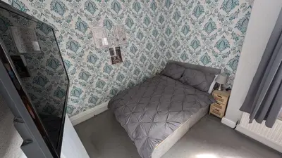 a small bed in a bedroom with wallpaper at Martell's Hotel in Blackpool