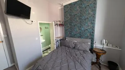 a bedroom with a bed and a tv on a wall at Martell's Hotel in Blackpool