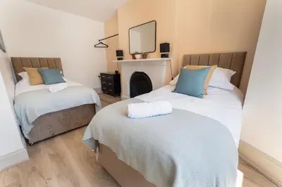 a bedroom with two beds and a mirror on the wall at Comfy 5 star Stays - 6 Bedrooms - Sleeps 8 - Free Parking & WiFi - Wirral in New Brighton