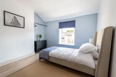 a bedroom with blue walls and a bed with a window at Comfy 5 star Stays - 6 Bedrooms - Sleeps 8 - Free Parking & WiFi - Wirral in New Brighton