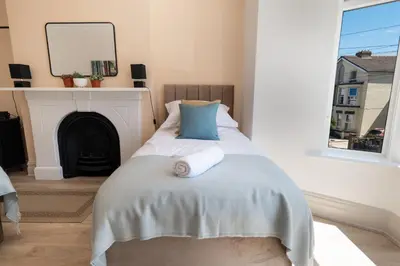 a bedroom with a bed with a mirror and a fireplace at Comfy 5 star Stays - 6 Bedrooms - Sleeps 8 - Free Parking & WiFi - Wirral in New Brighton