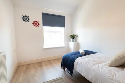 a white bedroom with a bed and a window at Red & Blue flat 15mins to Liverpool city centre, free parking in New Brighton
