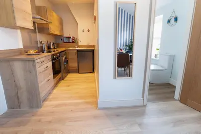 a kitchen with wooden cabinets and a table in a room at Red & Blue flat 15mins to Liverpool city centre, free parking in New Brighton