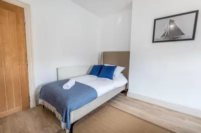 a small bedroom with a bed with blue pillows at Red & Blue flat 15mins to Liverpool city centre, free parking in New Brighton