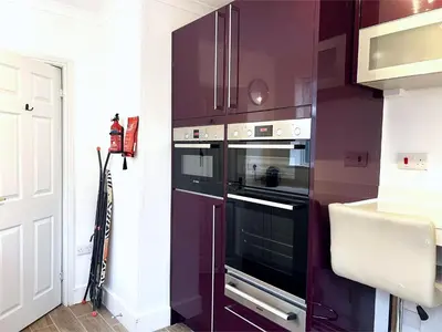 a kitchen with a purple wall with two ovens at Newly Renovated 3 Bedroom House, 6 beds with 2 showers, near University Town Centre in Lancaster