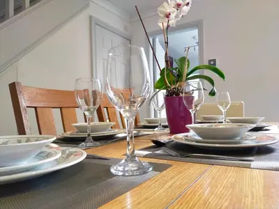 a table with glasses and plates and a plant on it at Newly Renovated 3 Bedroom House, 6 beds with 2 showers, near University Town Centre in Lancaster