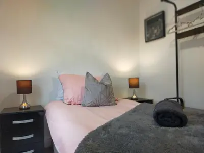 a bedroom with a bed with pink and grey pillows at Newly Renovated 3 Bedroom House, 6 beds with 2 showers, near University Town Centre in Lancaster