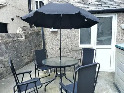 a table with chairs and an umbrella on a patio at Newly Renovated 3 Bedroom House, 6 beds with 2 showers, near University Town Centre in Lancaster