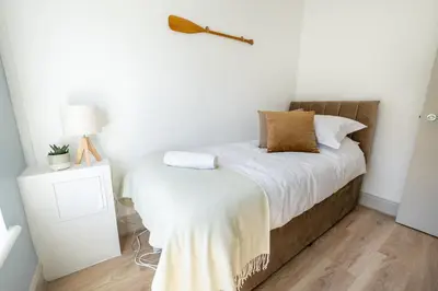 a bedroom with a bed with white sheets and a lamp at Terracotta Apartment, free WiFi & parking, coastal location in New Brighton
