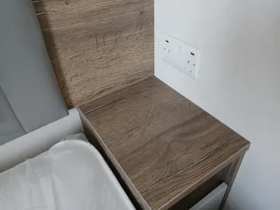 a wooden shelf next to a bed in a room at 3-Bed Caravan - Haven Lakeland Leisure Park in Grange Over Sands