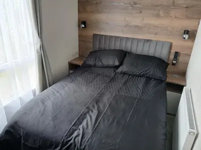 a bed in a bedroom with a wooden wall at 3-Bed Caravan - Haven Lakeland Leisure Park in Grange Over Sands