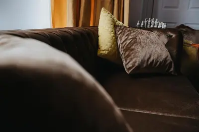 a brown couch with two pillows on it at Grand Victorian Villa 6 - En-Suites, Hot Tub, Cinema Room, Private Parking & Park View in Liverpool
