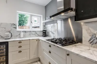 a kitchen with white cabinets and a stove top oven at Grand Victorian Villa 6 - En-Suites, Hot Tub, Cinema Room, Private Parking & Park View in Liverpool