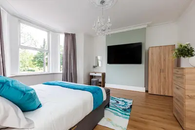 a bedroom with a bed and a flat screen tv at Grand Victorian Villa 6 - En-Suites, Hot Tub, Cinema Room, Private Parking & Park View in Liverpool