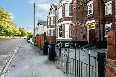 a black fence in front of a brick house at Grand Victorian Villa 6 - En-Suites, Hot Tub, Cinema Room, Private Parking & Park View in Liverpool