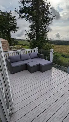 a patio with a couch on a wooden deck at Lake View - Beacon Fell View Holiday Park in Longridge