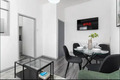 a dining room with a table and chairs and a clock at Residency apartments Liverpool in Liverpool