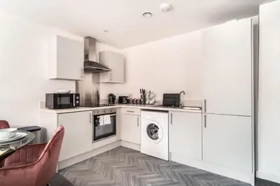 a kitchen with white cabinets and a washer and dryer at Lovely 1 Bed Central Preston Apartment in Preston