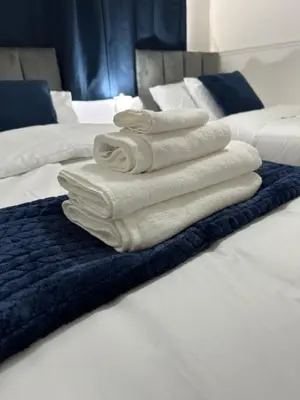 three towels are stacked on top of a bed at Affluent Living Property perfect for contractors and individuals in Wigan