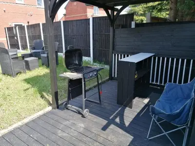 a grill and a table and a chair on a deck at Affluent Living Property perfect for contractors and individuals in Wigan