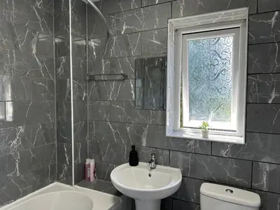a bathroom with a sink and a toilet and a window at Affluent Living Property perfect for contractors and individuals in Wigan