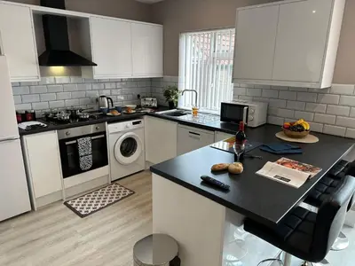 a kitchen with white cabinets and a black counter top at Entire House at Buckingham Road in Morecambe