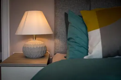 a lamp on a night stand next to a bed at Entire House at Buckingham Road in Morecambe