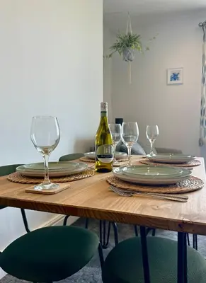a wooden table with glasses and a bottle of wine at Clock Tower Apartment No4 in Morecambe