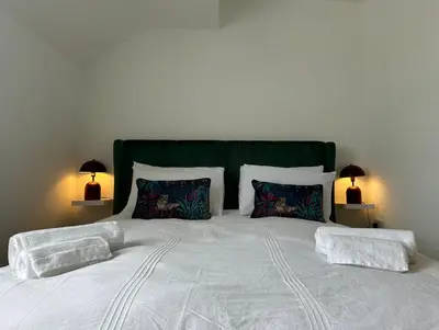 a white bed with two pillows and a green headboard at Clock Tower Apartment No4 in Morecambe